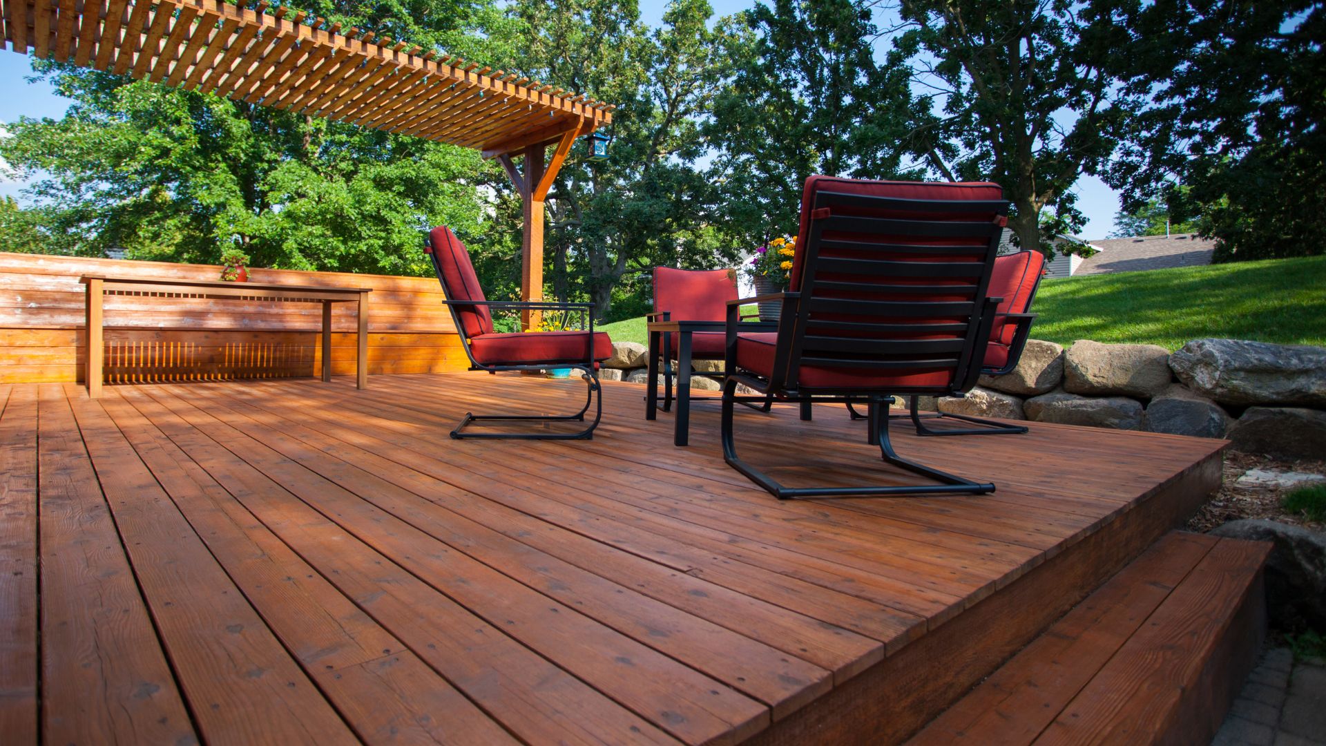 A wooden deck with chairs and a pergolated area