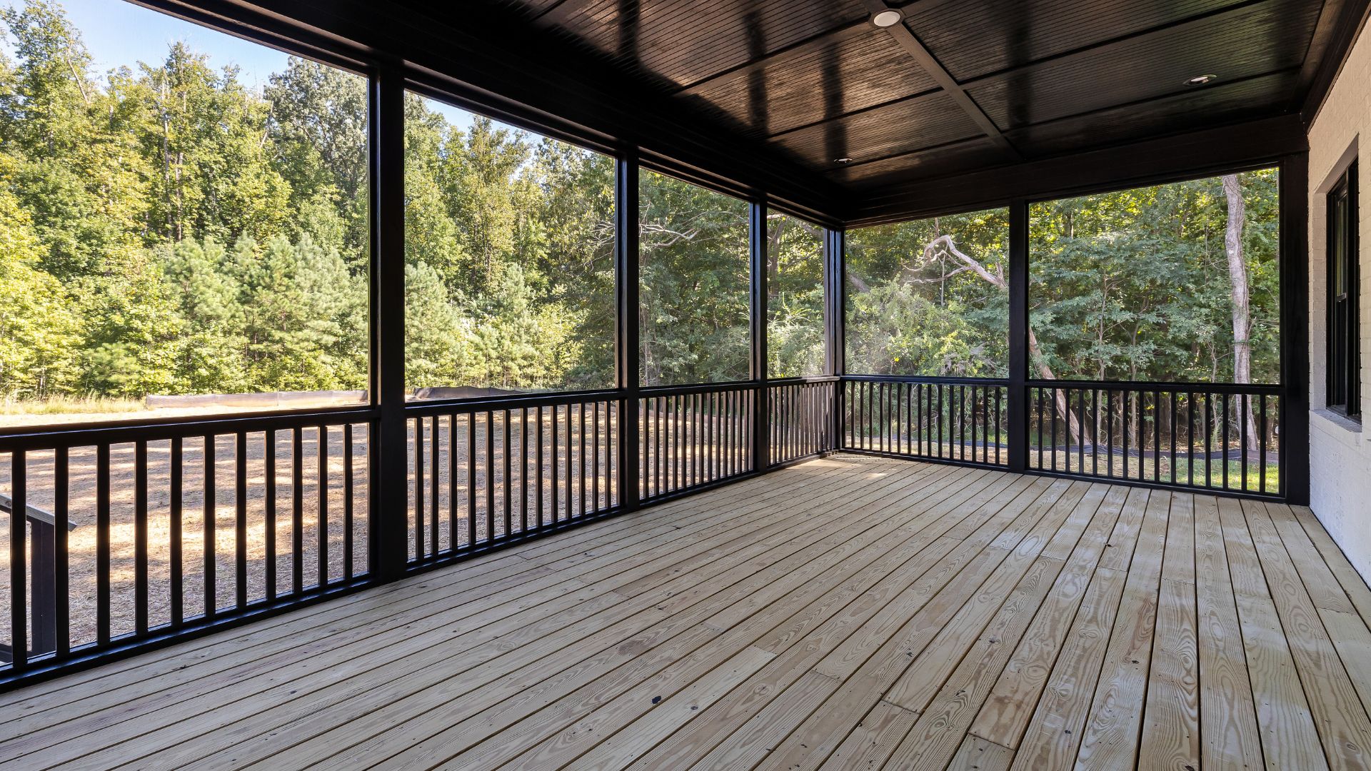 A covered porch with a view of a wooded area